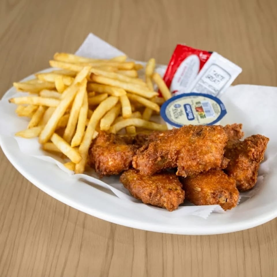 Crispy fried chicken wings and golden french fries with dipping sauces on a white plate.